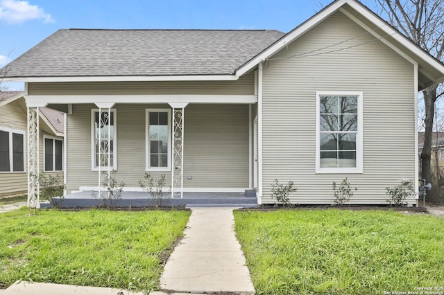 bungalow with a porch, roof with shingles, and a front lawn