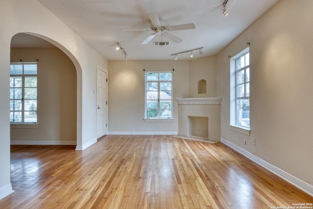 unfurnished living room featuring light wood finished floors, plenty of natural light, visible vents, and baseboards