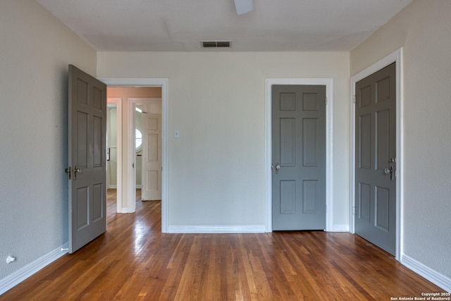 unfurnished bedroom with dark wood-type flooring, visible vents, and baseboards