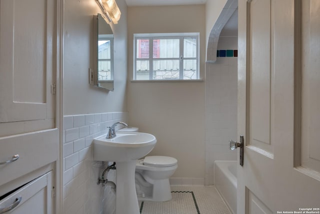 bathroom with toilet, tile patterned flooring, and tile walls