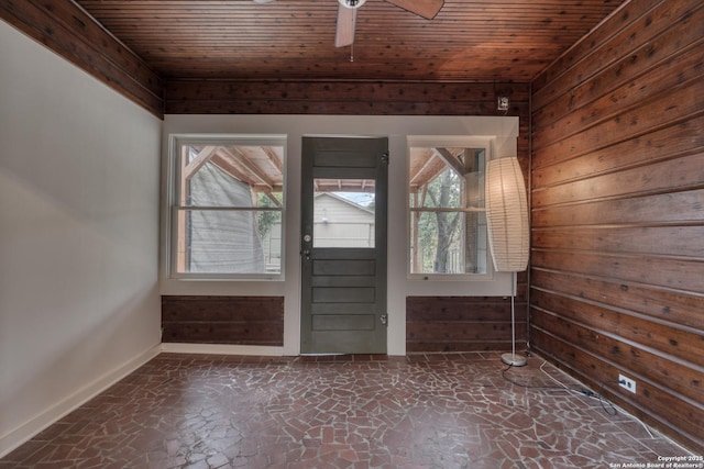 entrance foyer with wood ceiling, stone finish flooring, ceiling fan, wooden walls, and baseboards