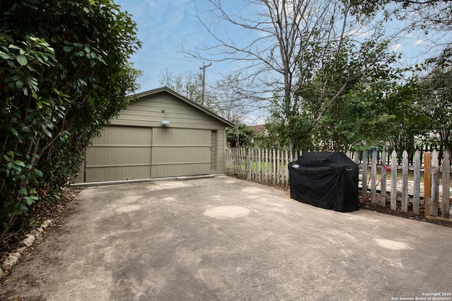 exterior space with an outbuilding, area for grilling, fence, and a detached garage