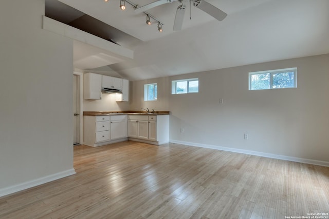 kitchen with light wood-type flooring, baseboards, white cabinetry, and open floor plan