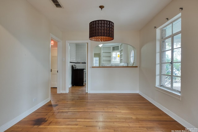 unfurnished dining area with visible vents, light wood-style flooring, and baseboards