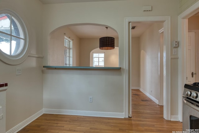 interior space with stainless steel gas stove, light wood finished floors, visible vents, and baseboards