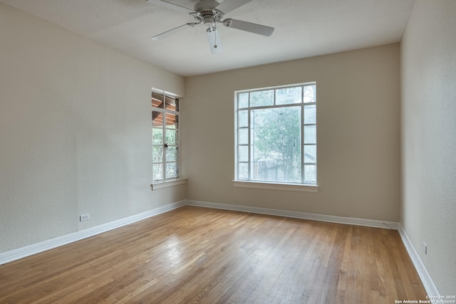 unfurnished room featuring a ceiling fan, light wood-style flooring, baseboards, and a wealth of natural light