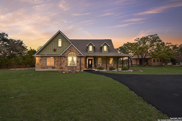 view of front of house featuring stone siding, a front lawn, and board and batten siding