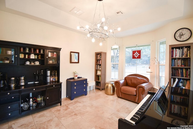 living area featuring a chandelier, a tray ceiling, and visible vents