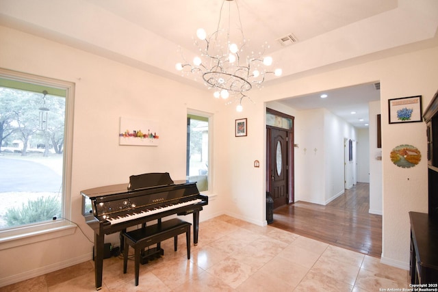 living area with a wealth of natural light, a raised ceiling, visible vents, and baseboards