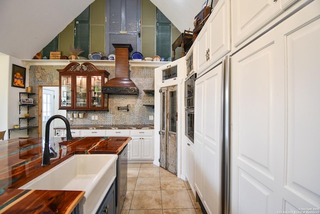 kitchen featuring light tile patterned floors, tasteful backsplash, appliances with stainless steel finishes, vaulted ceiling, and a sink