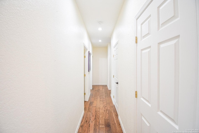 hallway with dark wood-type flooring, recessed lighting, and baseboards