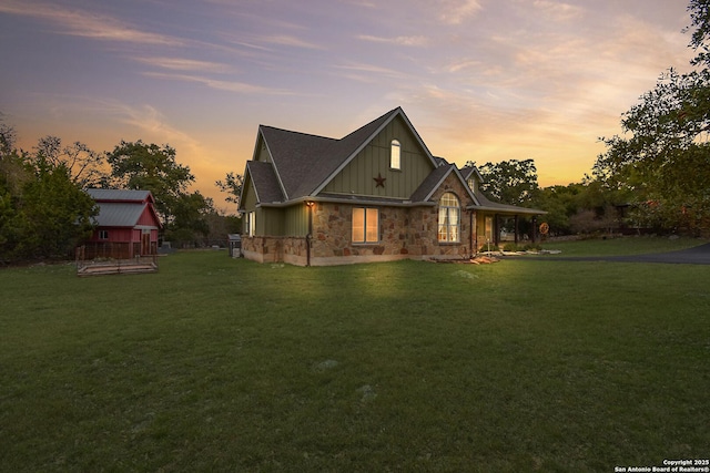 view of front facade with stone siding, a front lawn, and board and batten siding