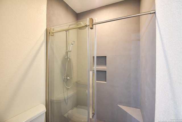 bathroom featuring toilet and a stall shower