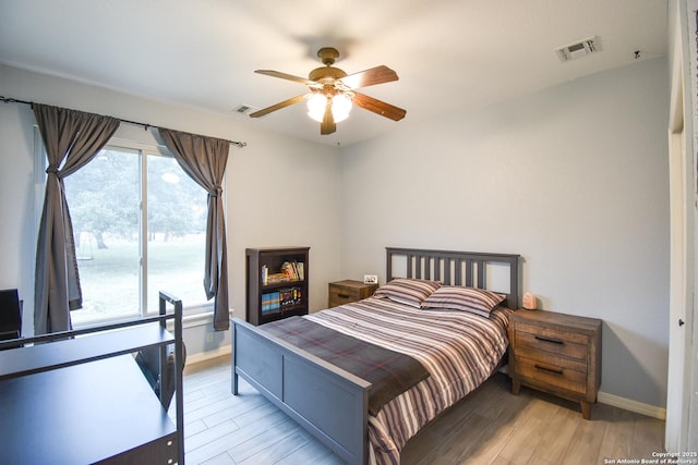 bedroom featuring baseboards, multiple windows, visible vents, and light wood-style floors