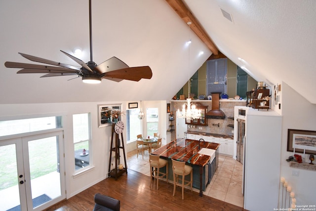 interior space with lofted ceiling with beams, light wood-style floors, white cabinets, french doors, and tasteful backsplash