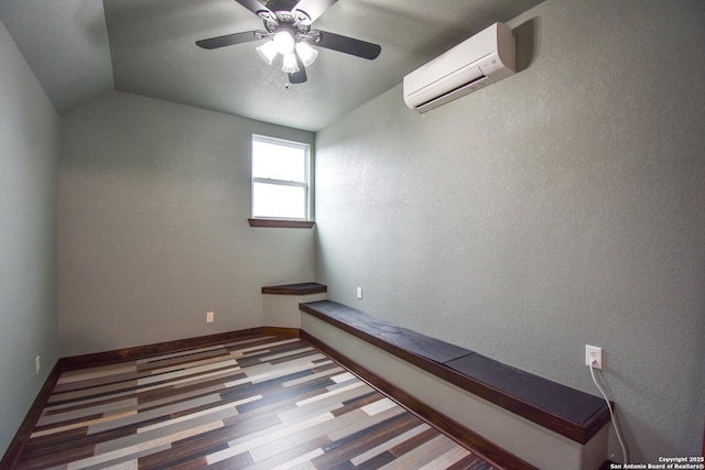 spare room featuring lofted ceiling, ceiling fan, a wall unit AC, and baseboards