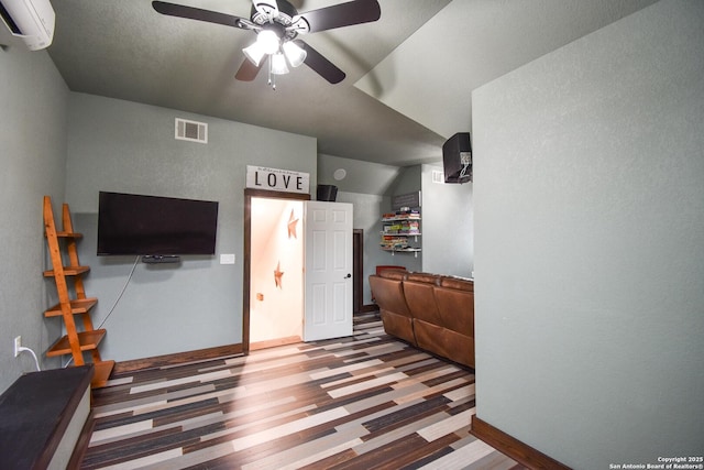 interior space with baseboards, visible vents, a ceiling fan, wood finished floors, and an AC wall unit