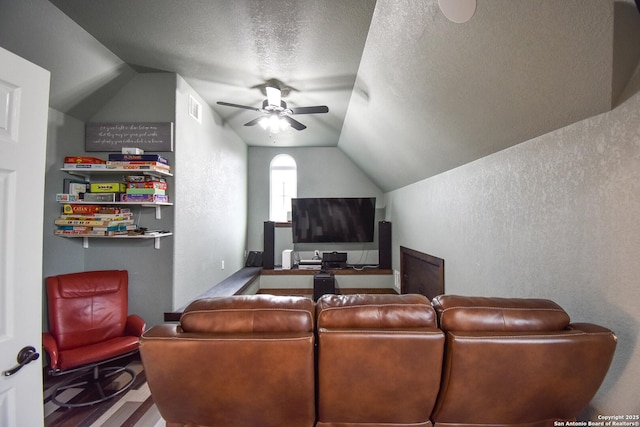 living area with lofted ceiling, a textured wall, a textured ceiling, ceiling fan, and visible vents