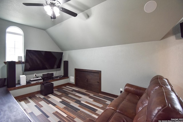 living area featuring vaulted ceiling, a ceiling fan, and baseboards