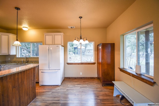 kitchen with visible vents, freestanding refrigerator, light stone countertops, pendant lighting, and a sink