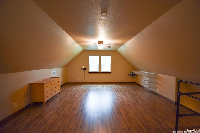 bonus room featuring visible vents, a ceiling fan, lofted ceiling, dark wood-style floors, and a textured ceiling