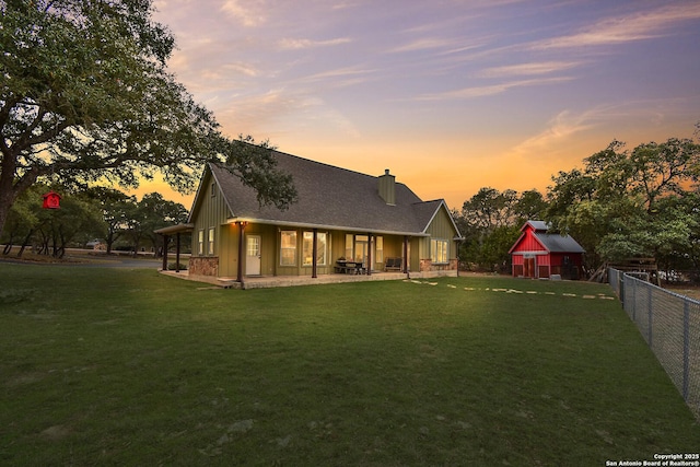 back of house featuring a chimney, a lawn, a patio area, and fence