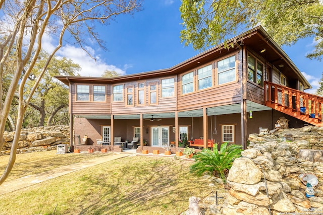 rear view of house with a yard, stucco siding, a ceiling fan, and a patio