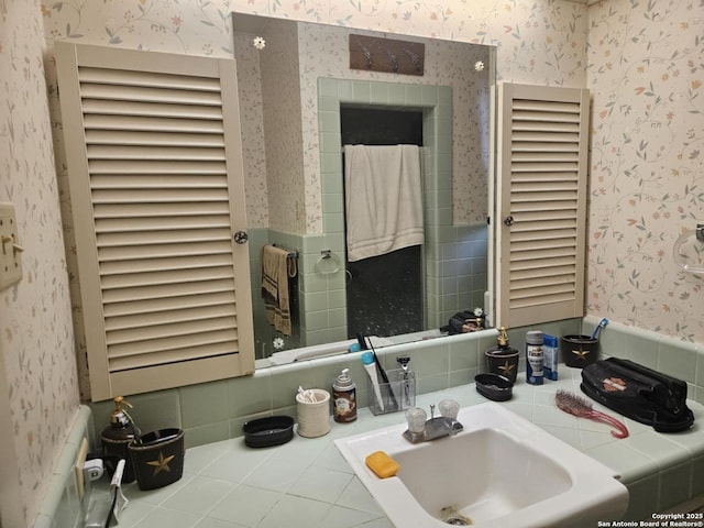 bathroom with wainscoting, a sink, and wallpapered walls