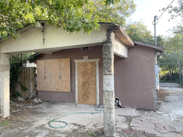 view of side of home featuring fence and stucco siding