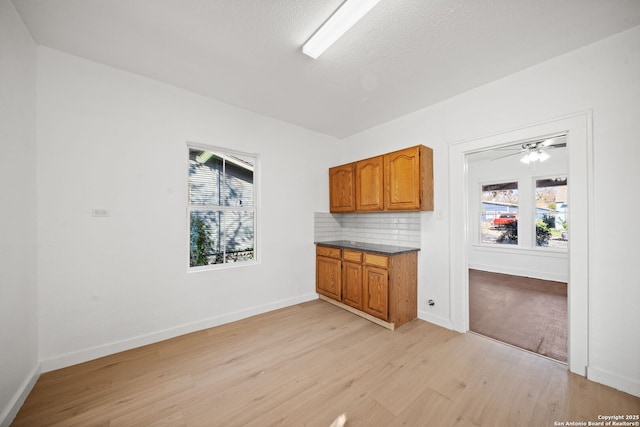 interior space featuring a textured ceiling, light wood finished floors, and baseboards