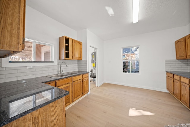 kitchen featuring brown cabinets, light wood finished floors, open shelves, and a sink