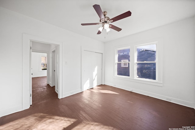 unfurnished bedroom with a ceiling fan, dark wood-style flooring, a closet, and baseboards