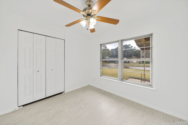 unfurnished bedroom with light floors, ceiling fan, baseboards, and a closet