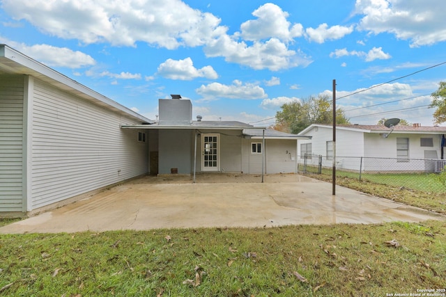 rear view of property with a yard, a patio, a chimney, and fence