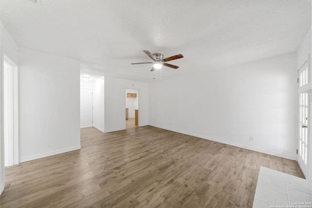 unfurnished room featuring baseboards, ceiling fan, a textured ceiling, and light wood finished floors