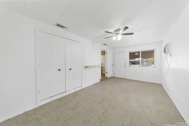 unfurnished bedroom with a wall unit AC, baseboards, visible vents, and a ceiling fan