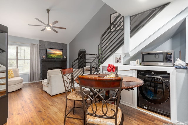 dining space with a ceiling fan, stairway, washer / clothes dryer, light wood-type flooring, and a brick fireplace