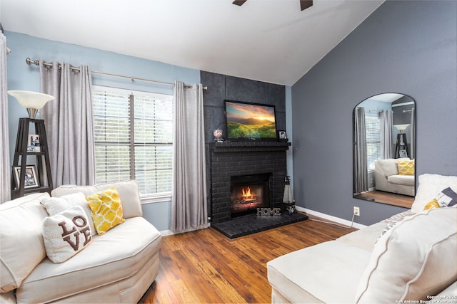 living room featuring arched walkways, a brick fireplace, vaulted ceiling, wood finished floors, and baseboards