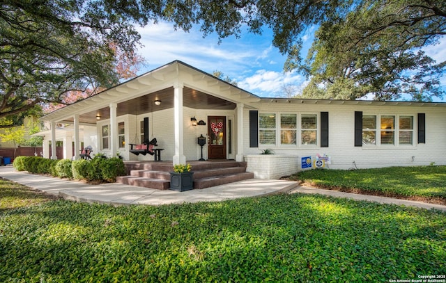 view of front of house featuring covered porch, a front yard, and brick siding