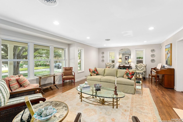 living area with crown molding, recessed lighting, visible vents, light wood-style floors, and baseboards