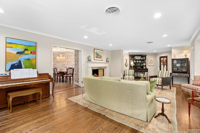 living area with crown molding, visible vents, a fireplace, and light wood-style flooring