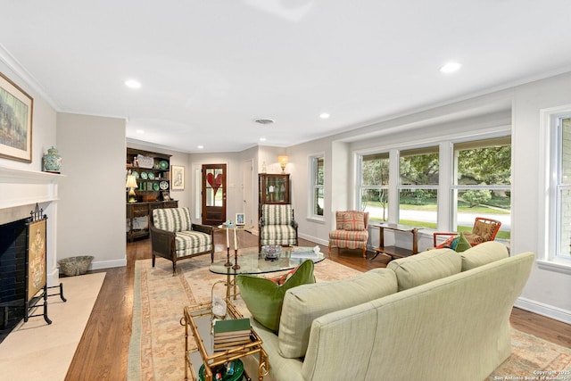 living area with recessed lighting, a fireplace, baseboards, light wood-style floors, and crown molding