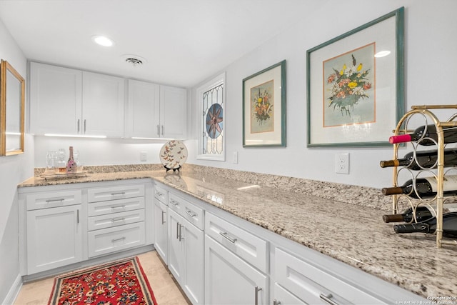 kitchen with light stone counters, white cabinets, and visible vents