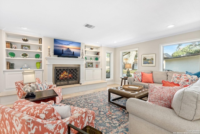 living area featuring ornamental molding, a warm lit fireplace, visible vents, and built in features