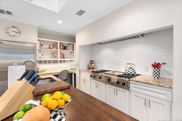 kitchen with visible vents, white cabinets, ornamental molding, light stone countertops, and stainless steel gas stovetop