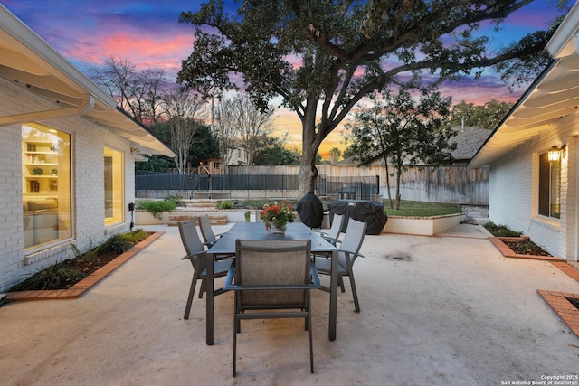 patio terrace at dusk featuring a fenced backyard and outdoor dining space