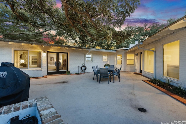 patio terrace at dusk featuring outdoor dining area and a grill