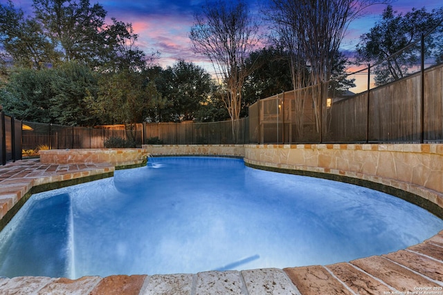 pool at dusk featuring a fenced in pool and a fenced backyard