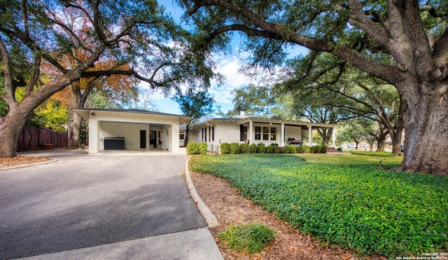 ranch-style home with aphalt driveway, a front yard, fence, and a carport