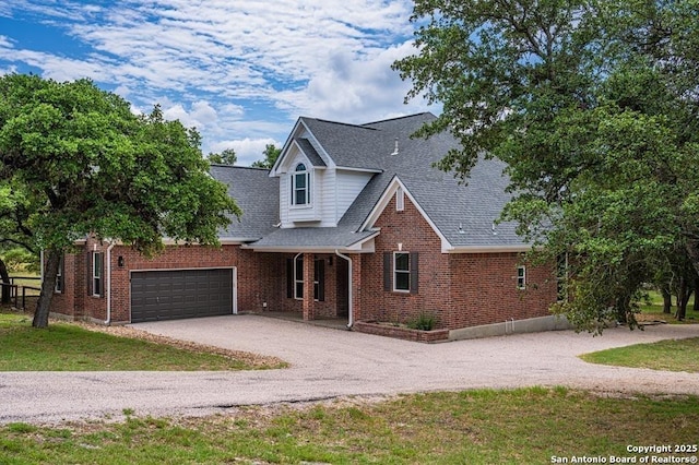 traditional-style home featuring driveway, roof with shingles, an attached garage, and brick siding